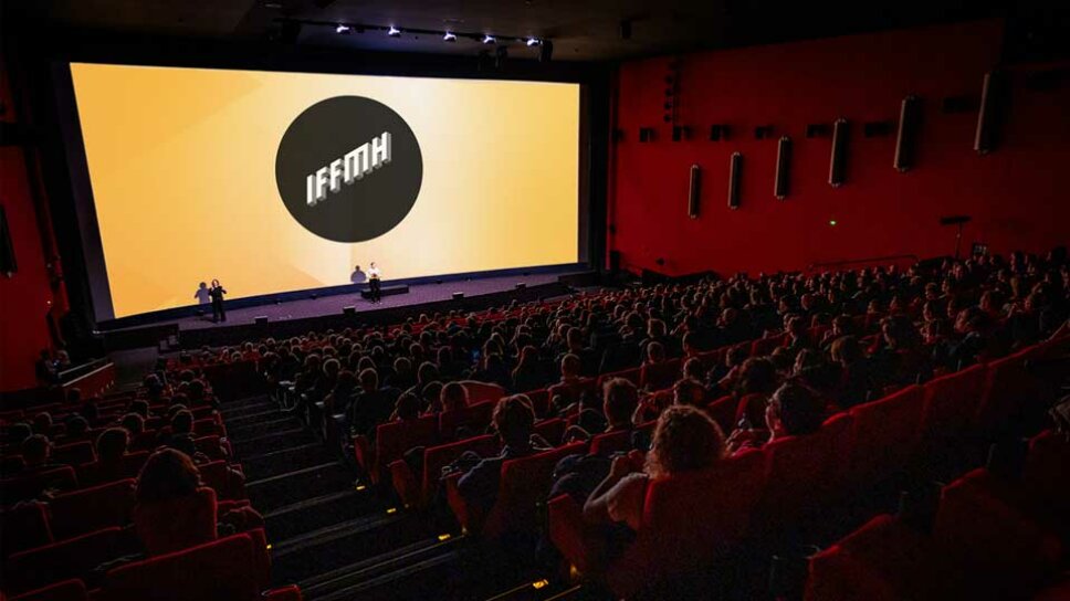 viele Personen sitzen im Kino vor einer Leinwand