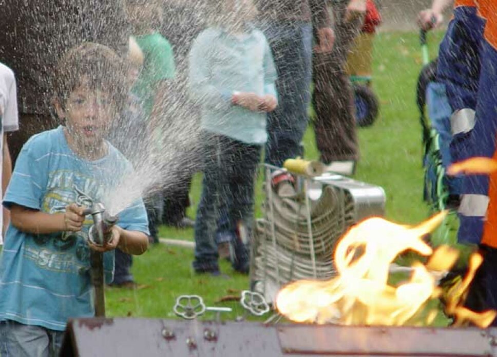 ein Junge übt das Löschen eines kleinen Feuers mit Wasser